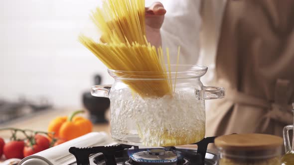 The Cook Puts The Pasta In The Water. Cooking Pasta In A Transparent Glass Saucepan