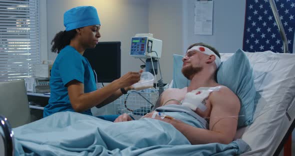 Nurse Feeding Injured Soldier in Hospital Bed