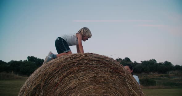 Mother Pushing Hay Roll with Child on Top of