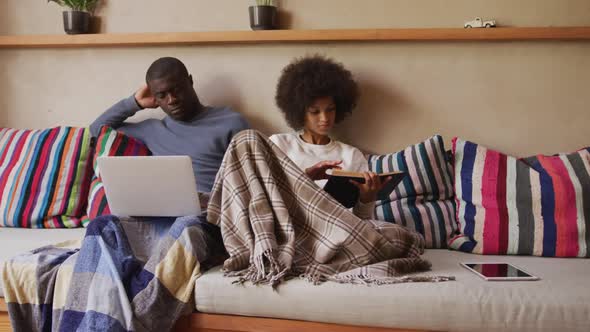 Couple sitting on the couch reading and using computer