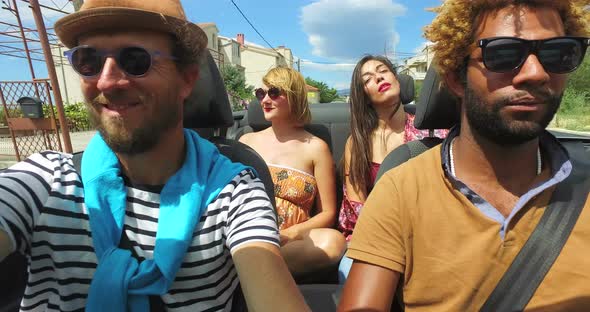 Four young people enjoying their road trip in convertible car