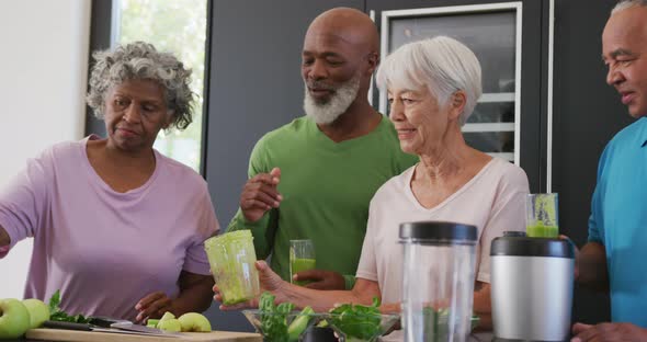 Happy senior diverse people making healthy drink in kitchen at retirement home