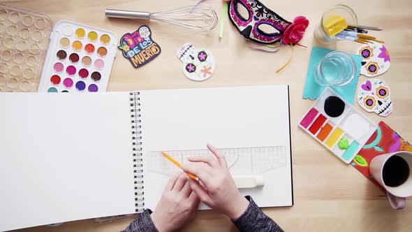 Step by step. Flat lay. Baker sketching a design of a cake for Dia de los Muertos holiday.