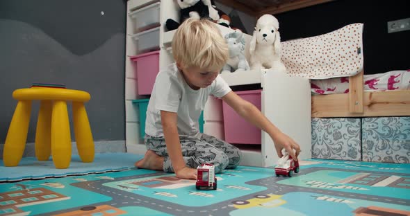 Cute Little Boy Playing with Toy Firetruck in Child Bedroom in Home