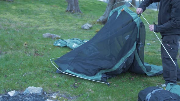 Young man securing tent poles camping MID SHOT 4K