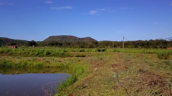 Tracking shoting slowly next to commercial fishing ponds on a fish farm in rural Brazil with mountai