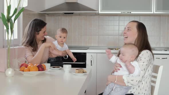 2 mothers with babies drink tea at home and chat. Friendly meeting, guests