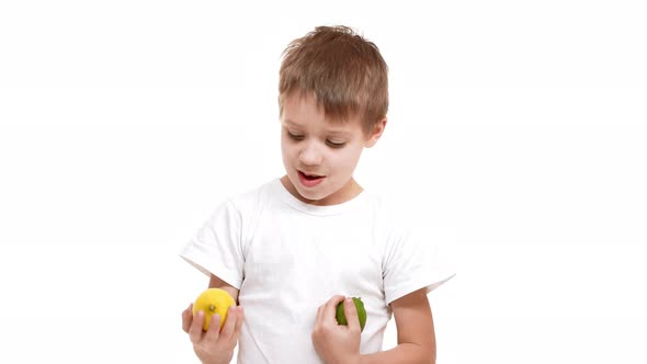 Elementaryschool Aged Caucasian Boy Standing on White Background and Holding Lemon and Lime in Hands