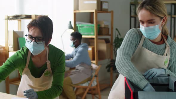 Female Coworkers in Masks Packing Eco Food Orders in Delivery Bag