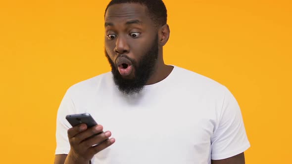 Amazed Black Man Holding Smartphone, Job Approval E-Mail, Yellow Background