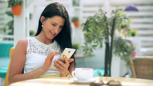 Young Woman Typing on Smart Phone in Cafe