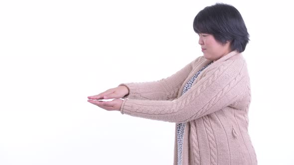 Happy Overweight Asian Woman Snapping Fingers and Showing Something for Winter