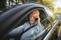 Smiling senior man talking on his cellphone in a car - PhotoDune Item for Sale
