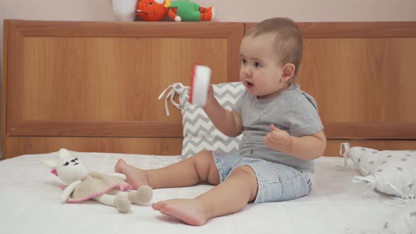 A baby girl 12-17 months old is playing with an alarm clock