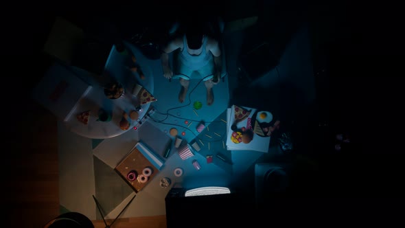 Aerial view for guy in the darkness watching tv surrounded by snacks and drinks