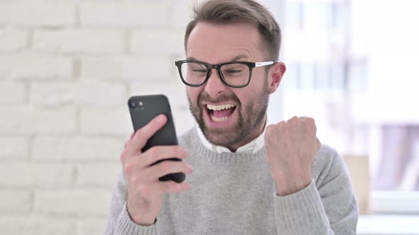 Creative Young Man Celebrating Success on Smartphone