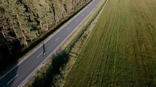 Aerial Video of Cyclist Riding a Road Bike on a Highway Near Field in Summer