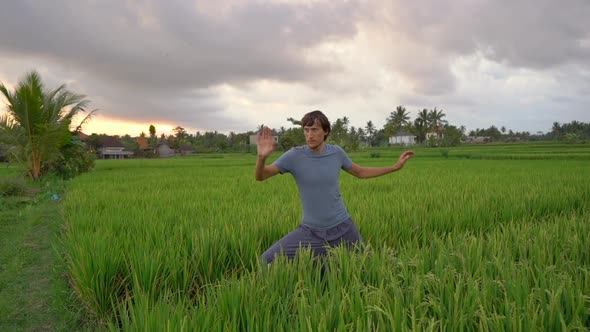 A Young Man Has a Yoga Training on a Beautiful Rice Field. Travel To Asia Concept. Slowmotion Video