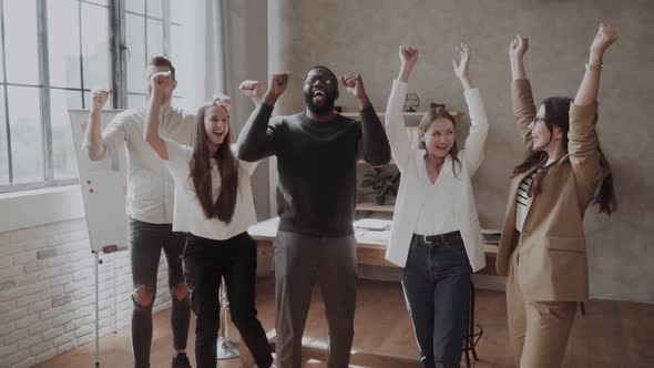 Excited Diverse Business Team in Casual Celebrate Hands Up Corporate Victory Together in Office