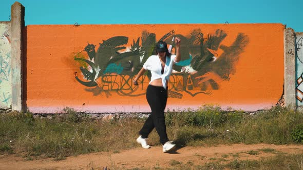 A Girl Dancing a Shuffle at the Orange Wall Actively Moving Her Legs