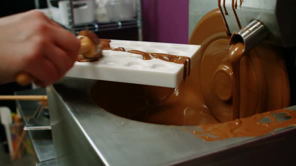 Worker filling mould with melted chocolate