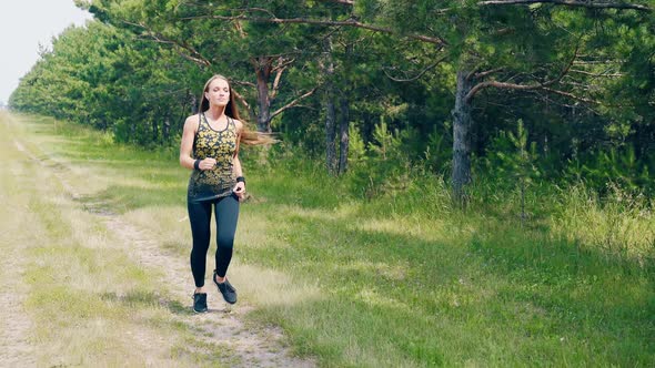 CU Portrait Young Pretty Girl Goes in for Sports in the Morning Runs Along a Pine Forest