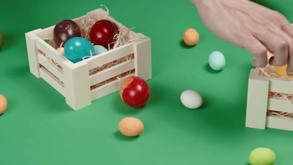 Hand of a Man is Placing Easter Colored Eggs on the Box