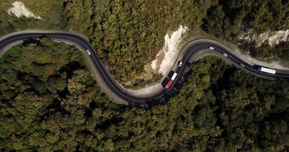 Aerial View of Car Driving Along The Winding Mountain Pass Road Through The Forest Trees. Autumn