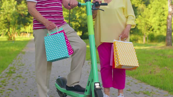 Senior Stylish Couple Grandmother Grandfather After Shopping with Bags Using Scooter for Riding