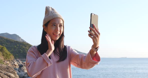 Woman taking selfie on cellphone with the sea background