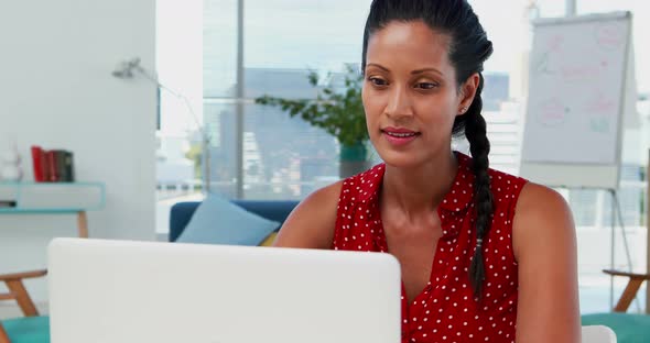 Female executive using laptop at desk 4k