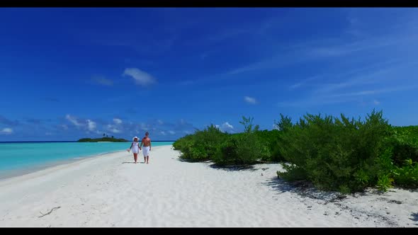 Family of two sunbathe on beautiful resort beach trip by turquoise ocean with white sandy background