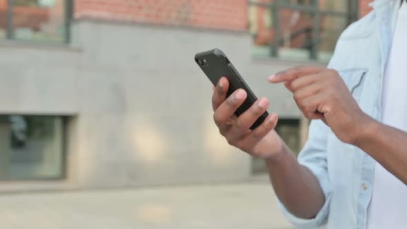 Close Up of Hands of African Man Using Smartphone While Walking in Street