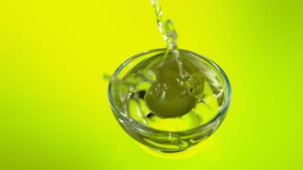 Super Slow Motion Shot of Green Olive Falling Into Fresh Olive Oil at 1000Fps.