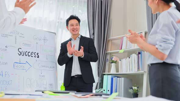 Asian businessman leader report work on whiteboard to colleagues team while brainstorm in office.