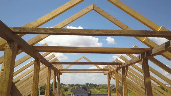 Aerial view of unfinished house with wooden roof frame structure under construction.