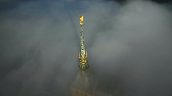 Atmospheric Aerial Close-up Shot of Glowing Golden Statue on Top of Mont Saint Michel Castle Steeple