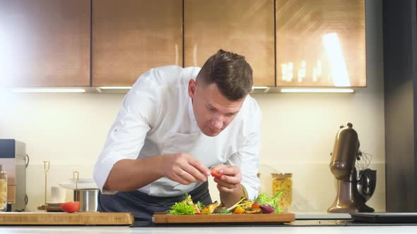 Male chef cuts cooked hot steak into thin slices on wooden cutting Board knife