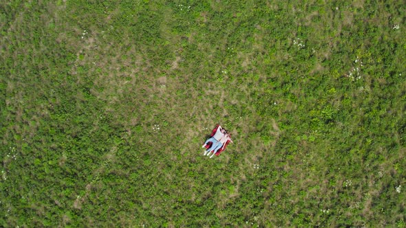 Happy Young Couple Lying on the Grass in the Meadow. Aerial Head over shot.