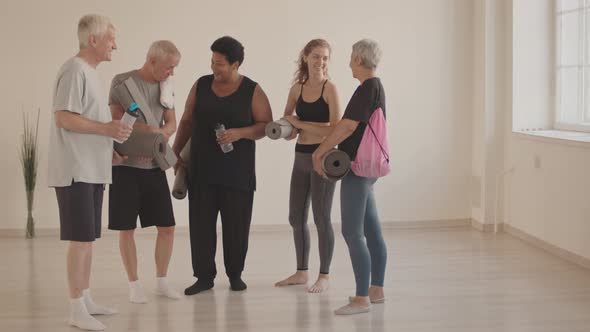 Group of Active Seniors and Trainer Talking before Yoga Class