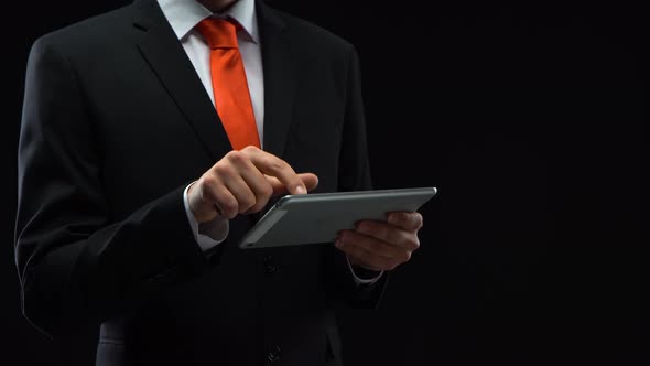 Businessman in Black Suit Working with a Tablet in His Hand Presses His Finger in Front of Himself