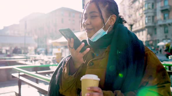 Young woman with face mask talking on smart phone on street, Italy