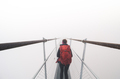 Female tourist walking across a suspension bridge in heavy fog - PhotoDune Item for Sale