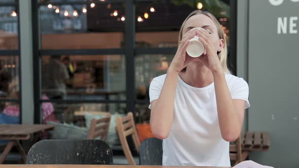 Portrait of Young Beautiful Woman Sitting in a Cafe Outdoor Drinking Coffee