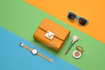 tials accessories, cosmetic makeup. Trendy Clutch, sunglasses. Coloful orange green party girl Set. Creative pop art fashionable vibrant concept