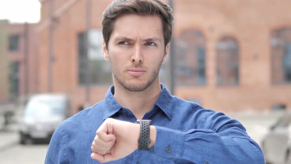 Outdoor Portrait of Waiting Young Man Watching Time on Watch