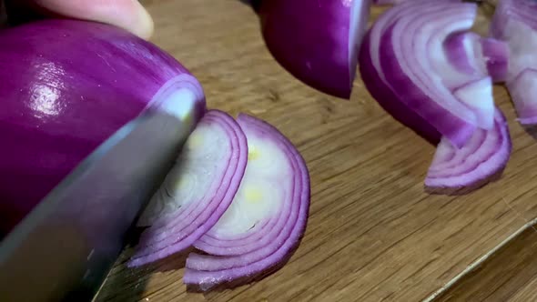 Cutting Red Onion with Kitchen Knife on Cutting Board on Chopping Board