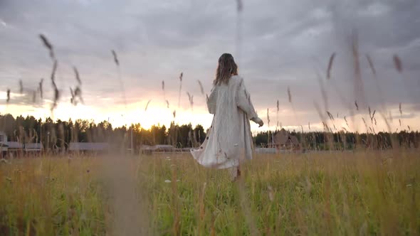 Happy Woman Running in Rural Field Towards Sunset Sky