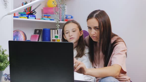 A Woman and Her Daughter are Doing Homework Together on a Laptop During the Pandemic and Distance