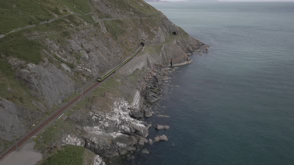 Train Entering Railway Tunnel In Coastal Cliff In County Wicklow, Ireland. aerial